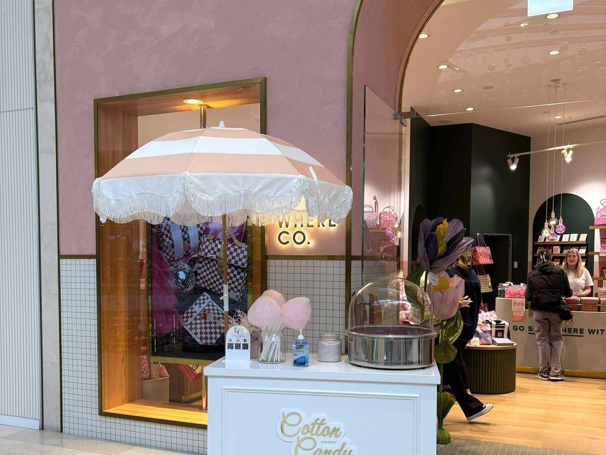Cotton candy cart with pink and white umbrella, live spinning machine