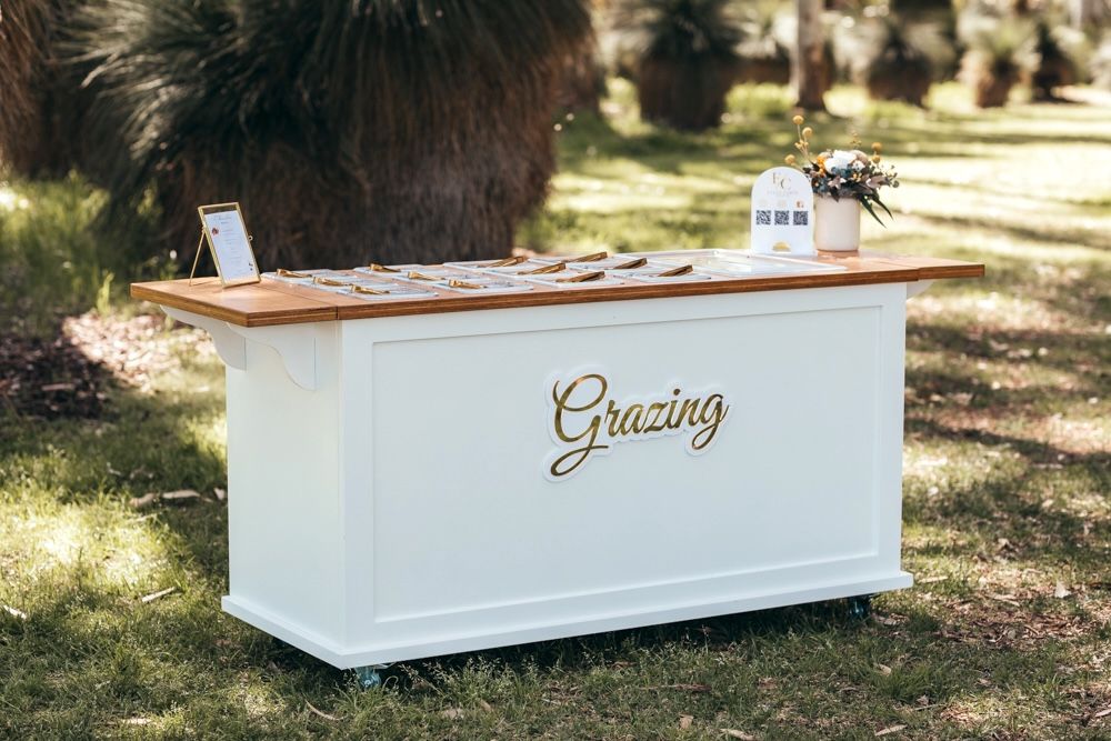Grazing cart with gold script lettering in a garden setting