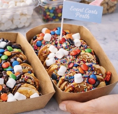 Mini pancakes cart with toppings and fringed parasol umbrella
