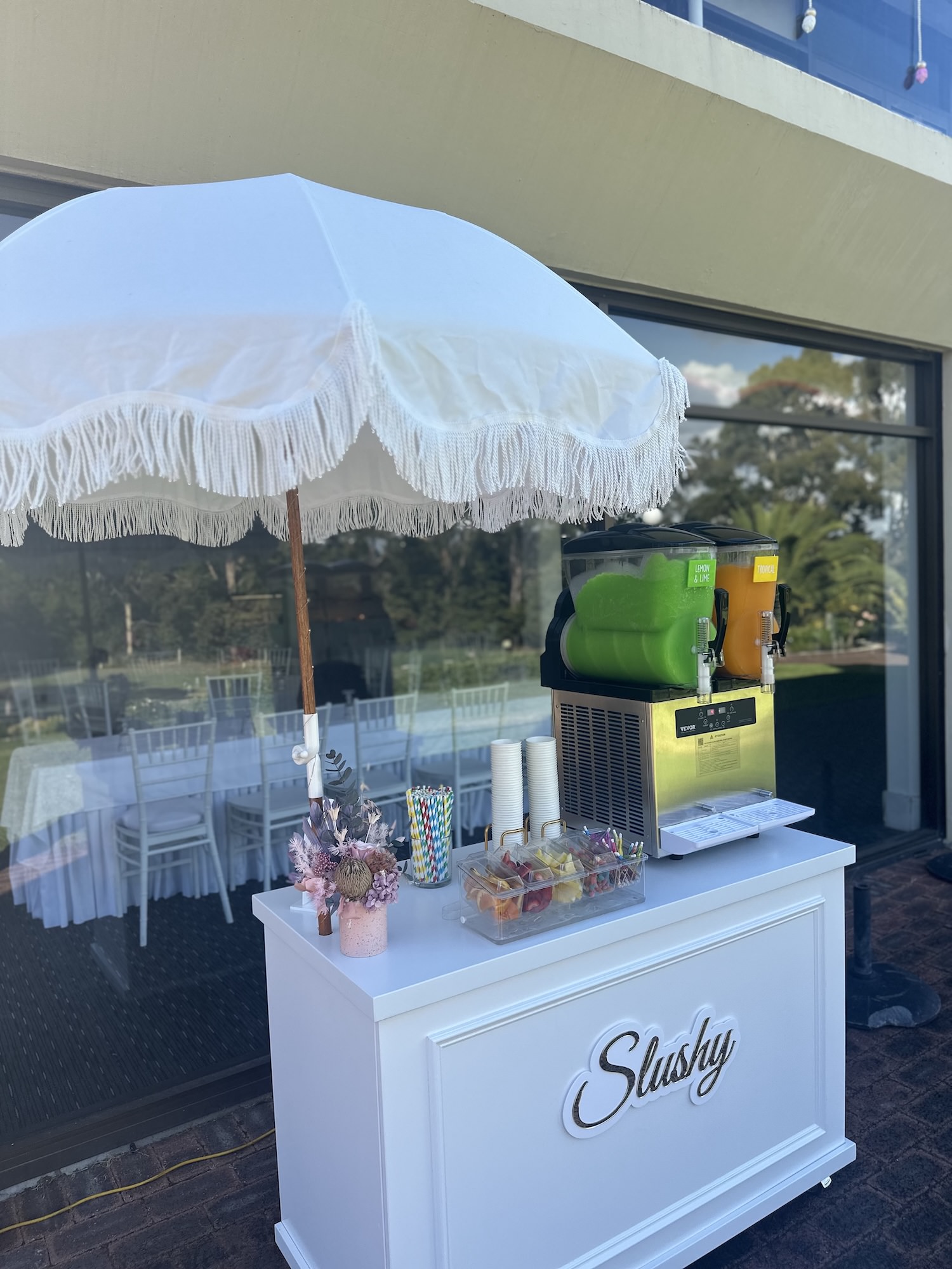 All-white slushy cart with slushy machine and fringed parasol umbrella
