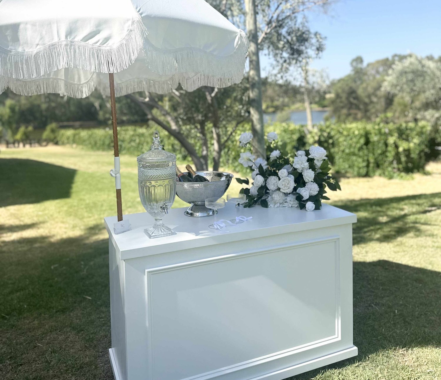 Elegant white wedding cart with champagne bowl, flowers and fringed parasol