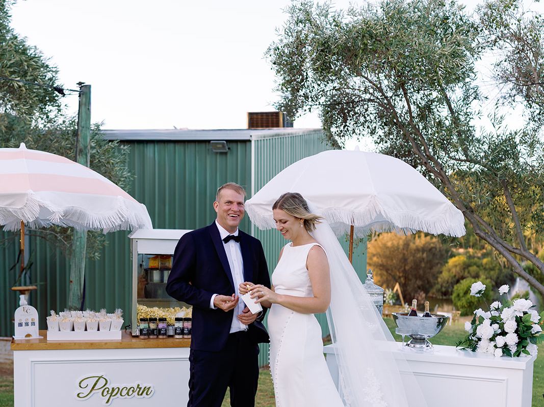 Newlywed couple with styled drinks cart at garden wedding